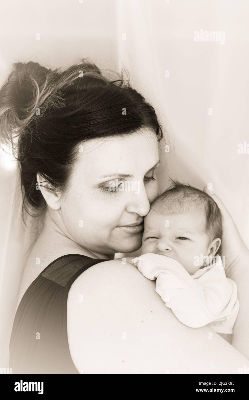Mom cuddle a newborn baby. Mother holds the kid on hands. Black and white Stock Photo