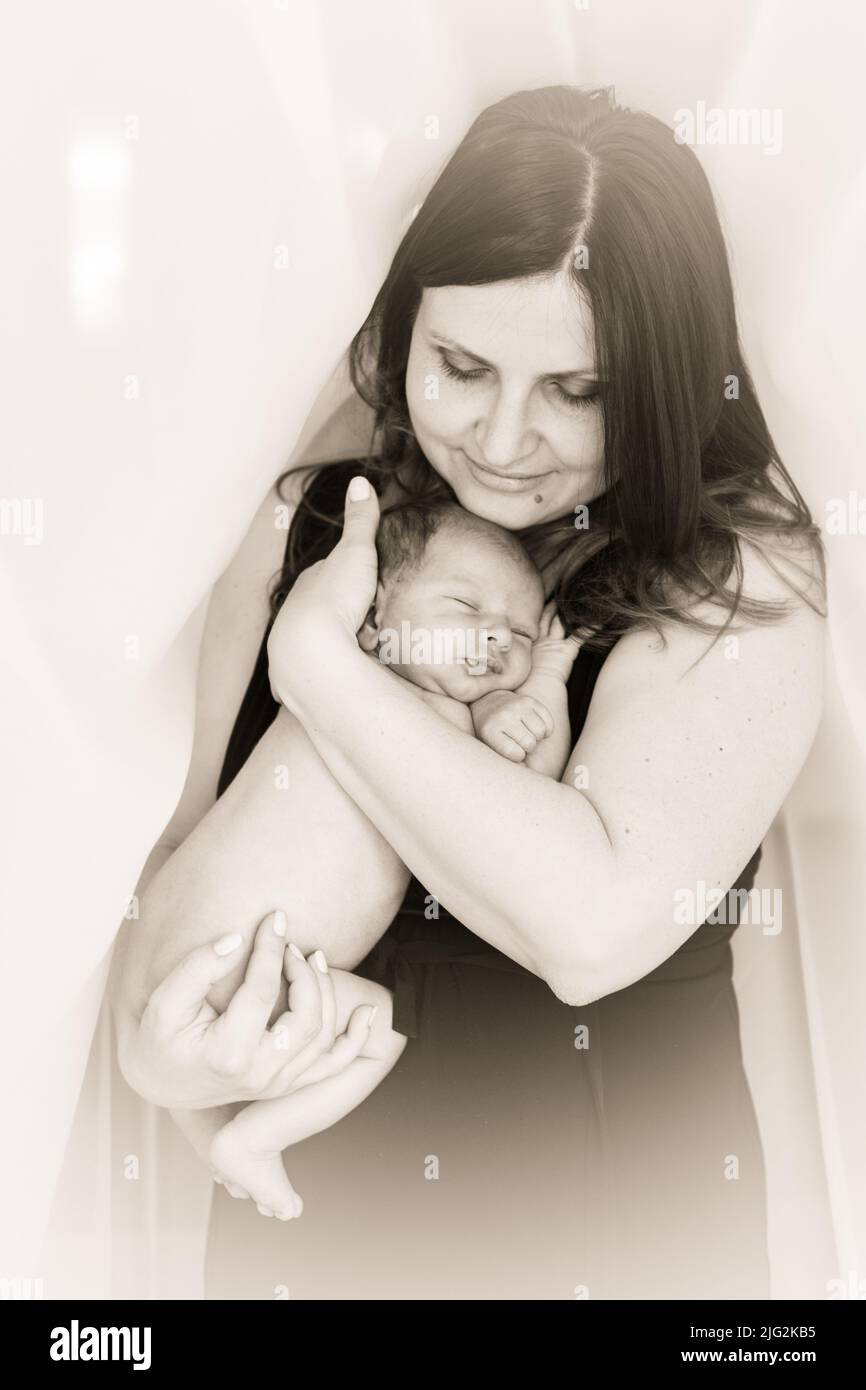 Mom cuddle a newborn baby. Mother holds the kid on hands. Black and white Stock Photo