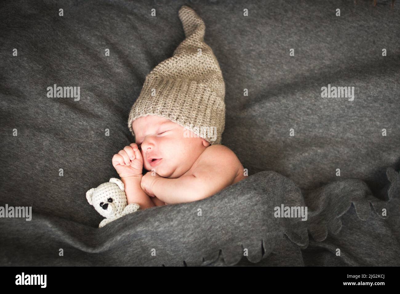 newborn baby sleeping with a toy next to the knitted teddy bear. Stock Photo