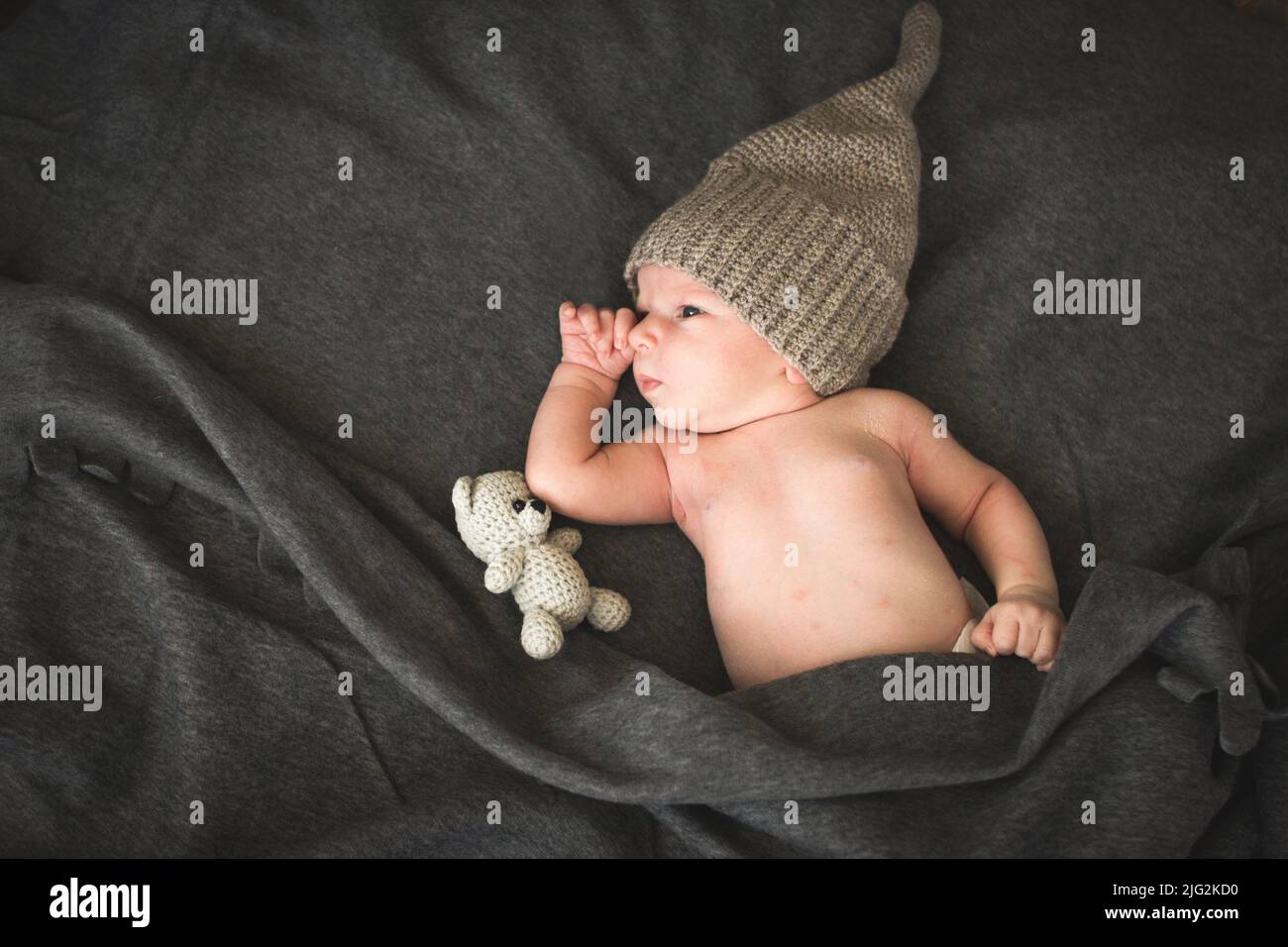 newborn baby with a toy lying next to the knitted teddy bear. Stock Photo