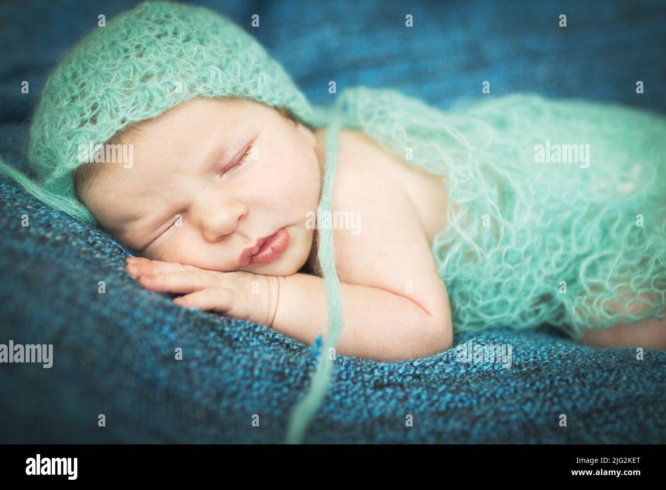 newborn baby sleeping sweetly on a blue background Stock Photo