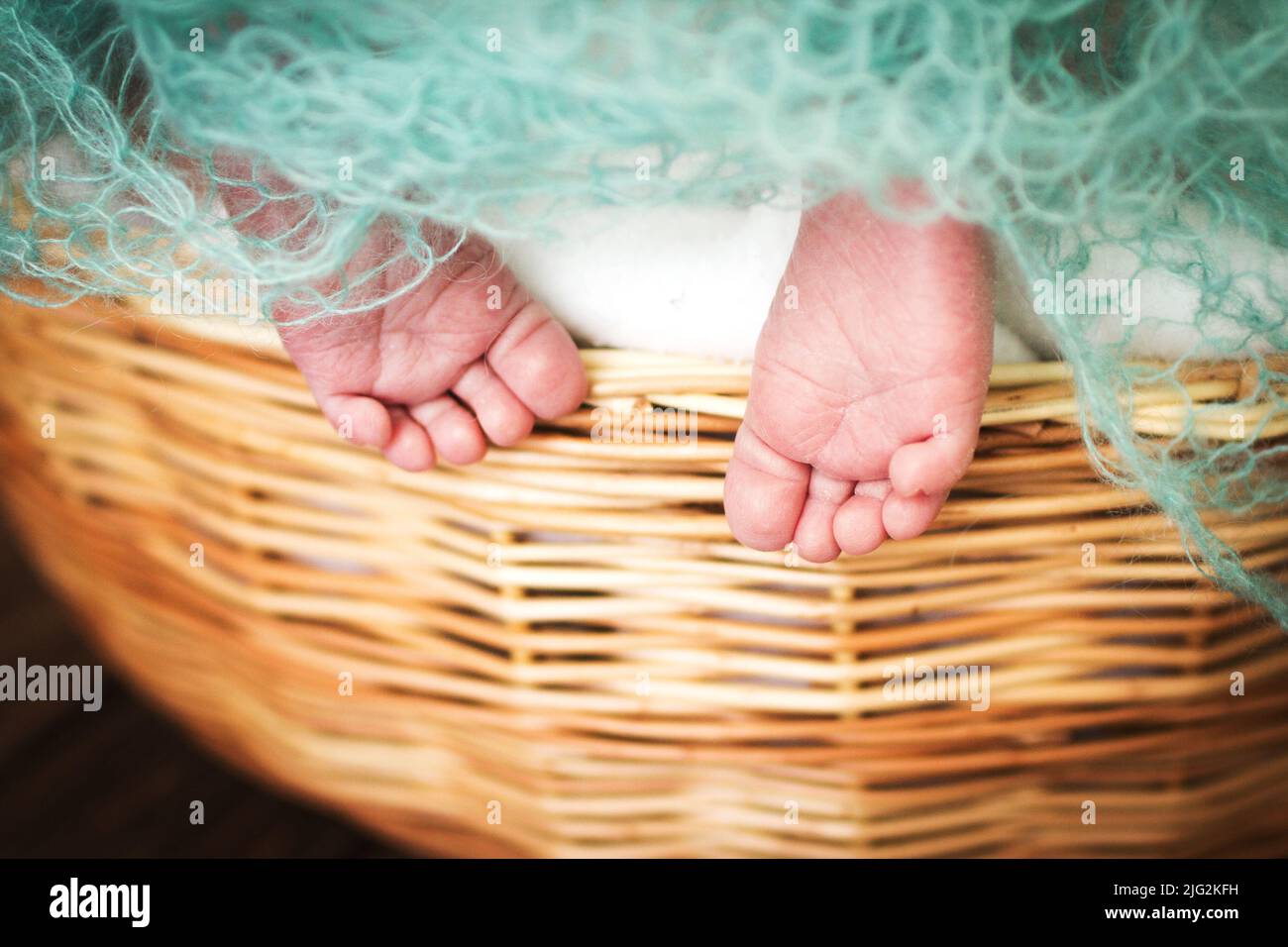 barefoot newborn baby feet. kids legs in the wicker basket. Stock Photo