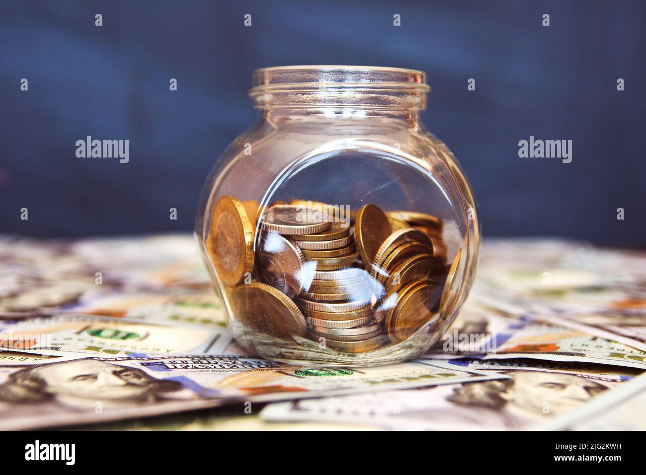 Glass jar with coins on the black background. A lot of dollar bills. Stock Photo