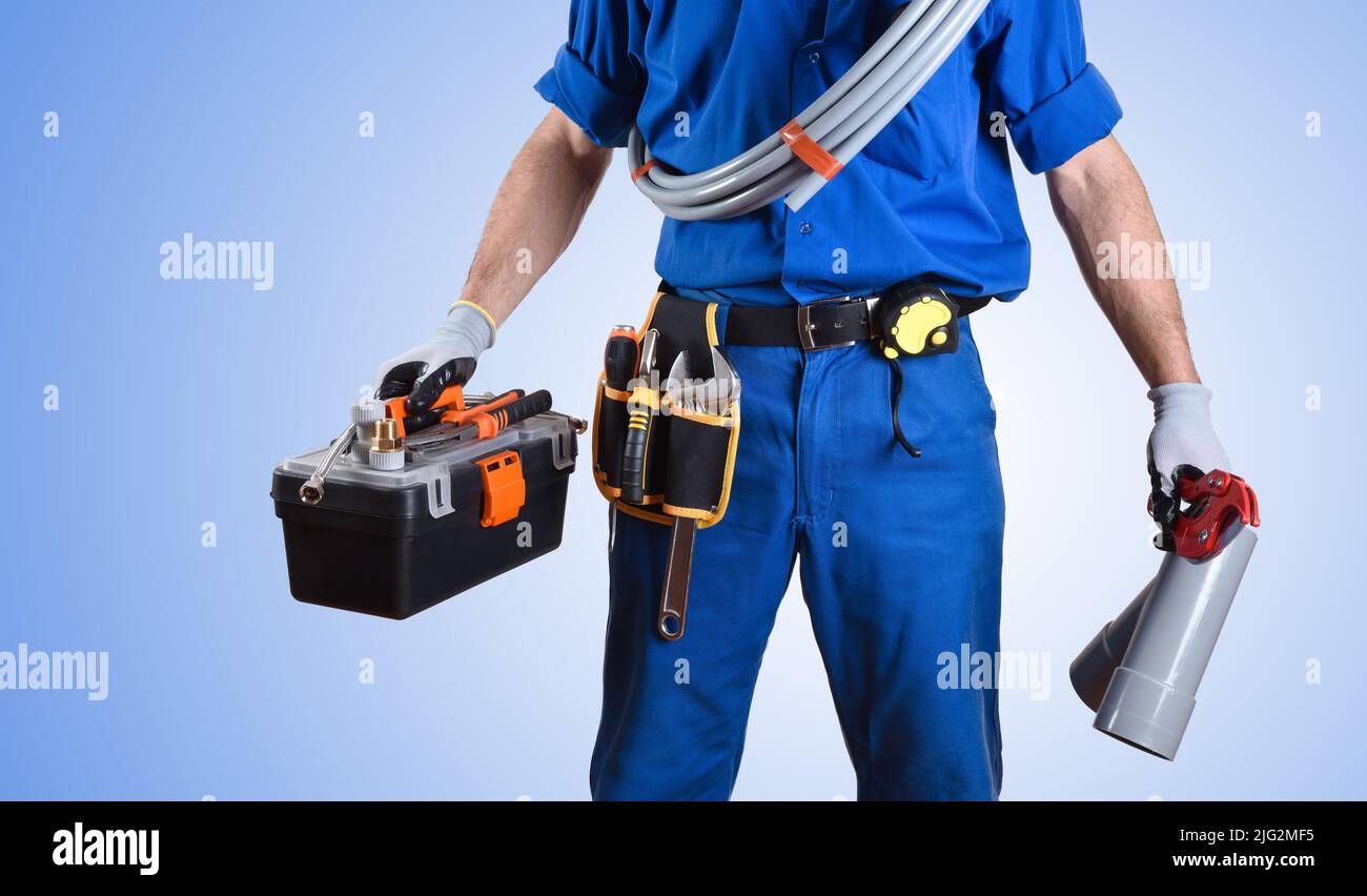 Detail of uniformed plumber with work tools in hands and blue gradient isolated background. Front view. Horizontal composition. Stock Photo