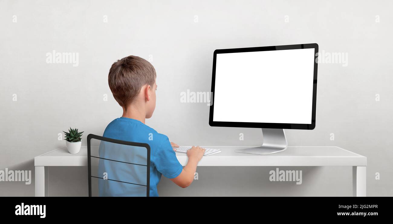 Boy working on the computer mockup. Isolated displaz screen for web page promotion. Back view of boz and work desk Stock Photo
