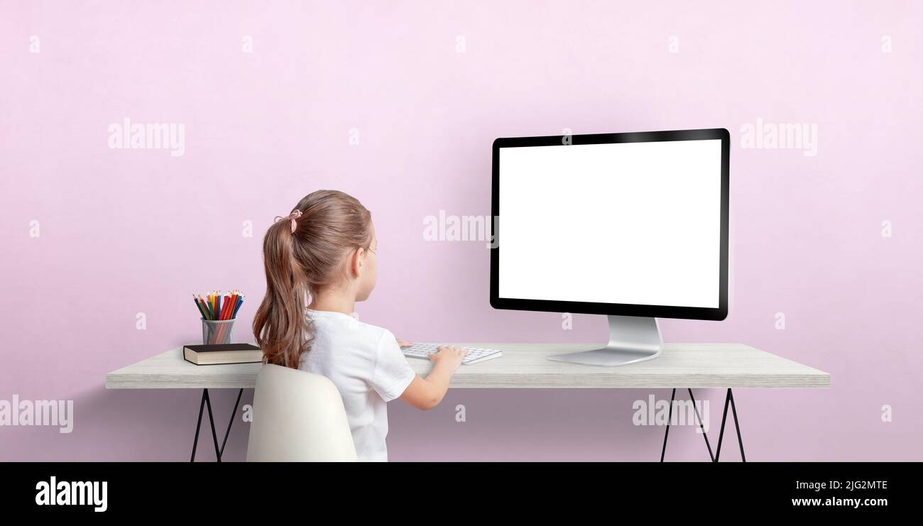 Young girl work on computer concept. Isolated computer display for mockup. Work room with pink wall. Back view Stock Photo