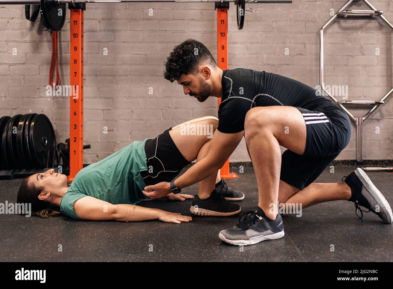 Personal trainer with a firsttime trainee correcting habits in the