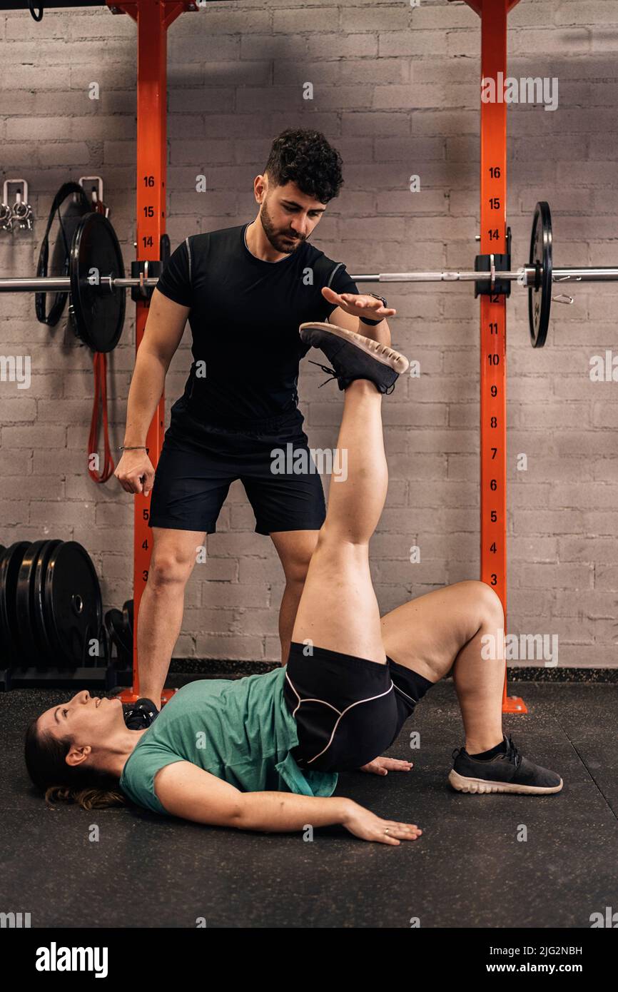 Personal trainer with a first-time trainee correcting habits in the ...