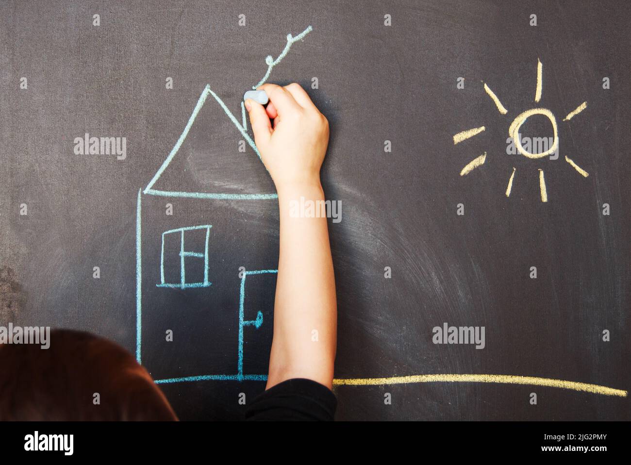 child draws on blackboard chalk house Stock Photo