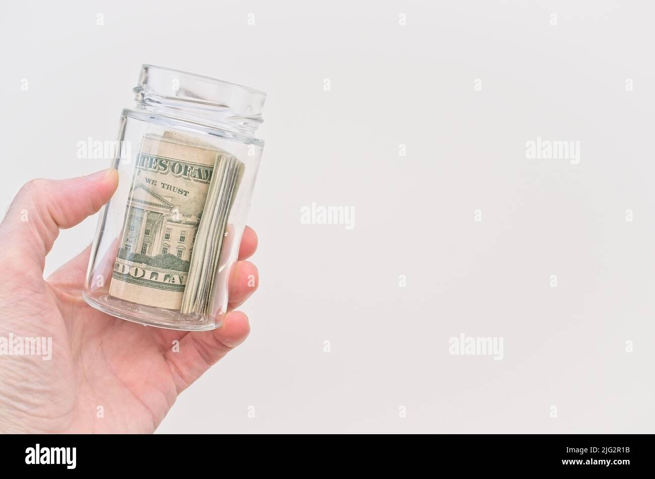 US banknotes roll in a glass jar with white background Stock Photo - Alamy