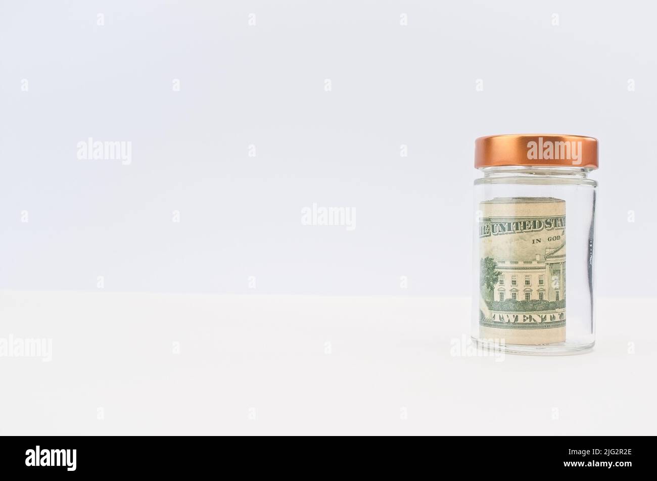 US banknotes roll in a glass jar with white background Stock Photo - Alamy