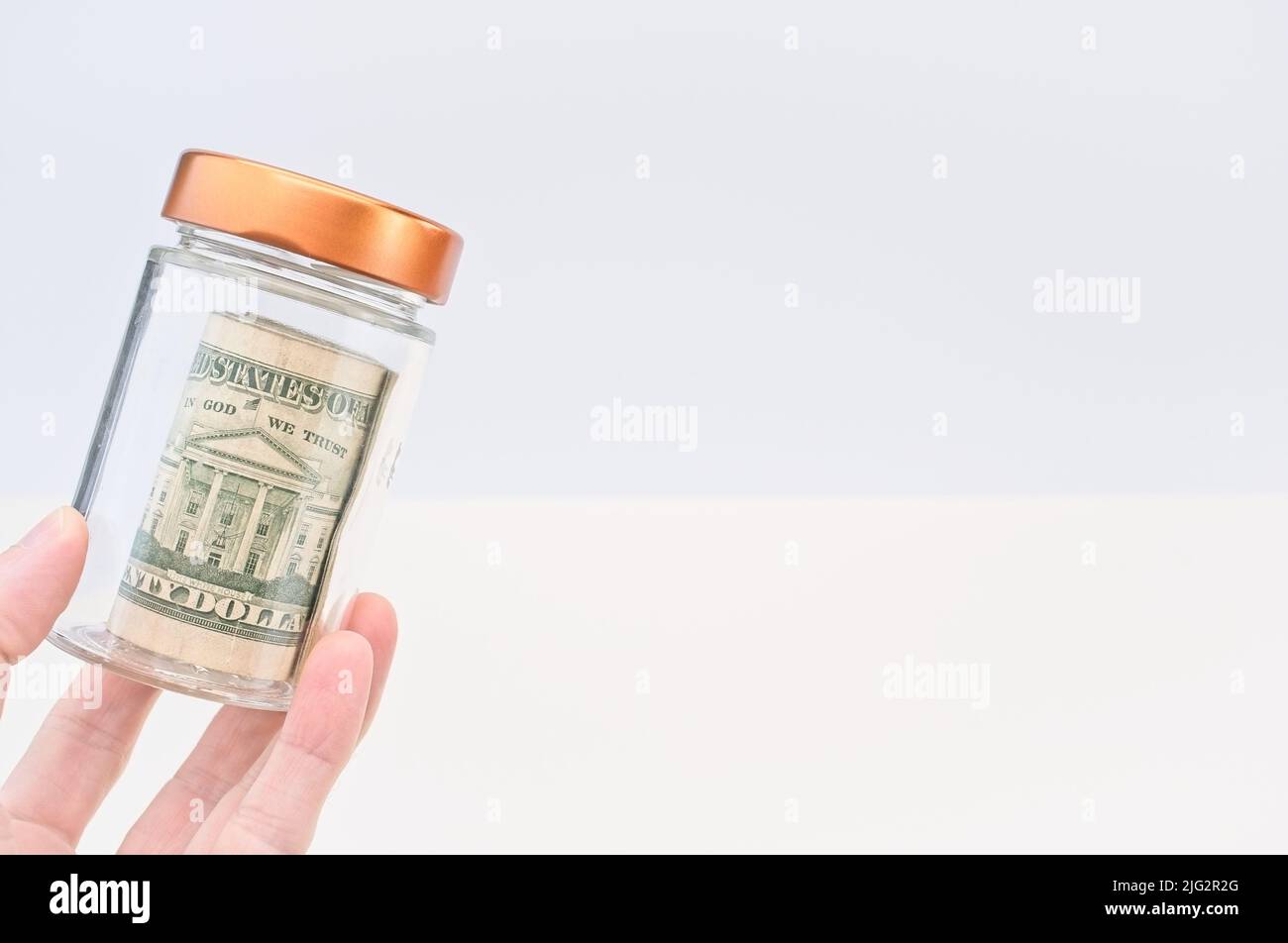 US banknotes roll in a glass jar with white background Stock Photo - Alamy