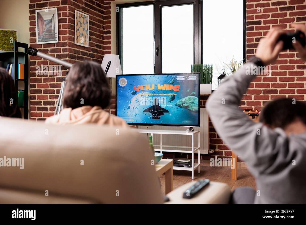Diverse people sitting in living room while enjoying gaming on ...