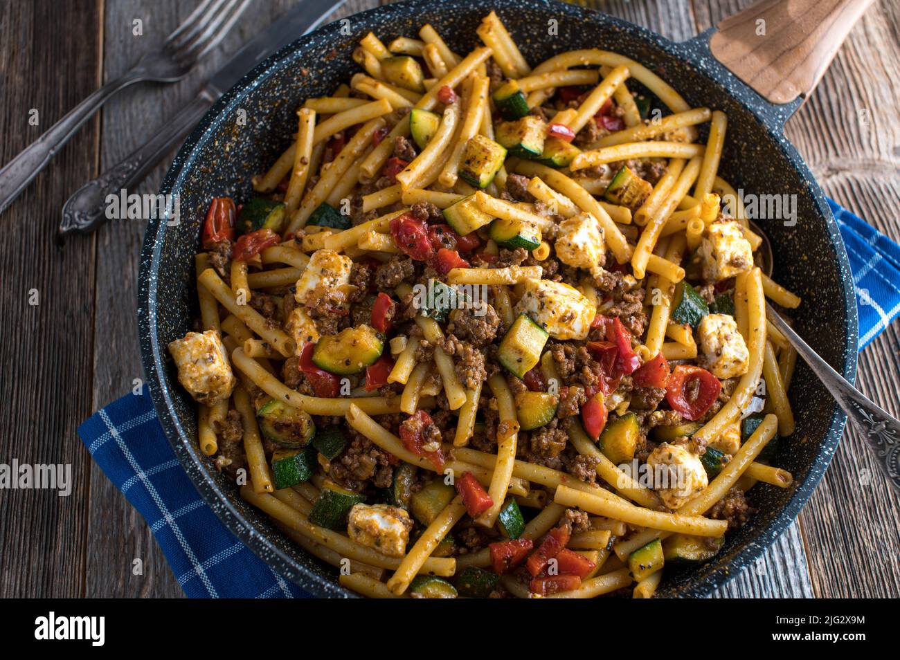 Greek pasta dish with macaroni, ground beef, vegetables and feta cheese in a frying pan Stock