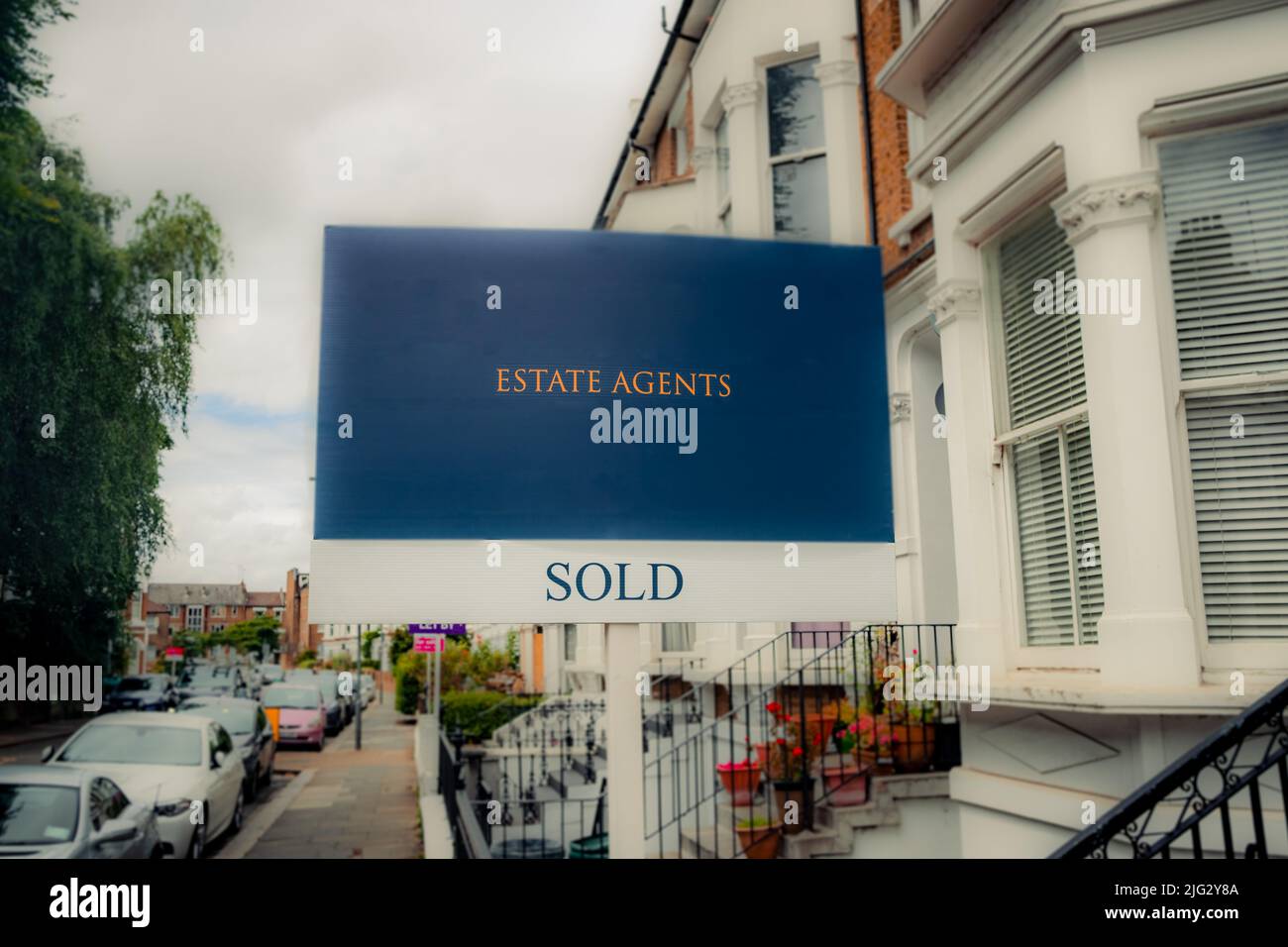 Estate agent SOLD sign with defocussed street of houses in background Stock Photo