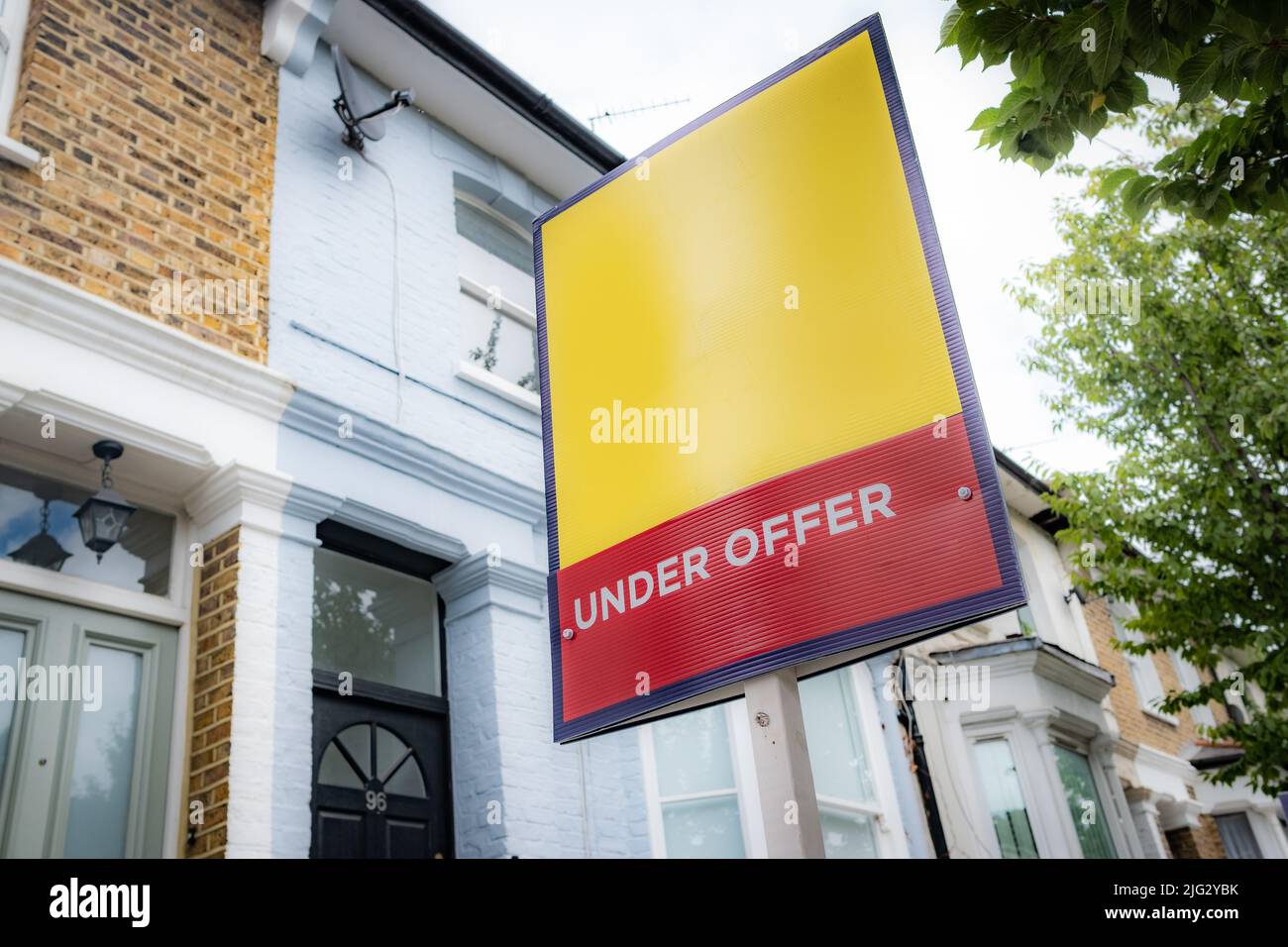 Estate agent 'Under Offer' sign on street of suburban British houses Stock Photo
