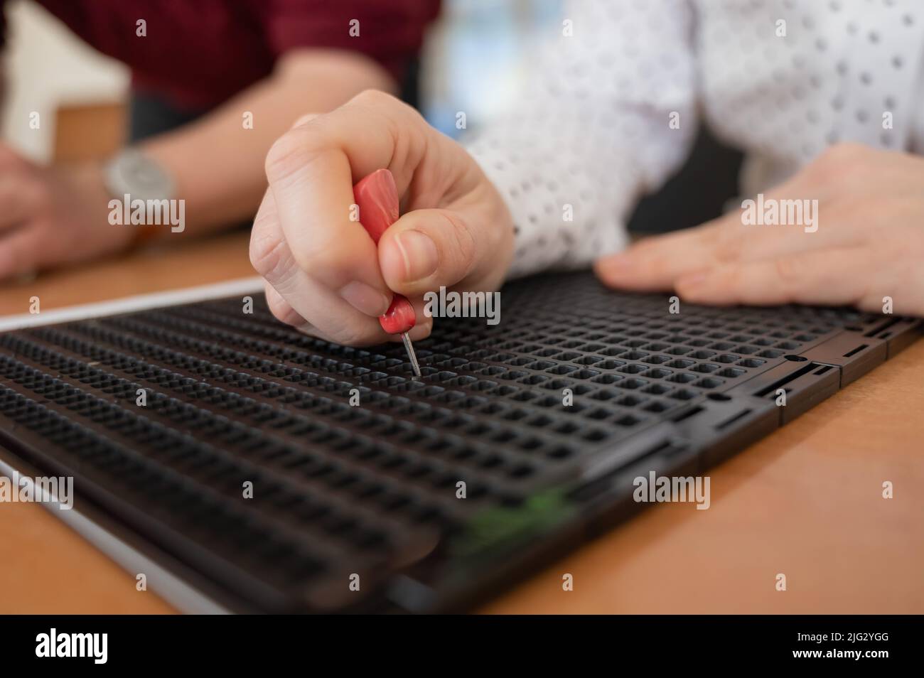 Using Stylus Letter Formation A woman uses a special stencil and stylus to write a letter in braille ...