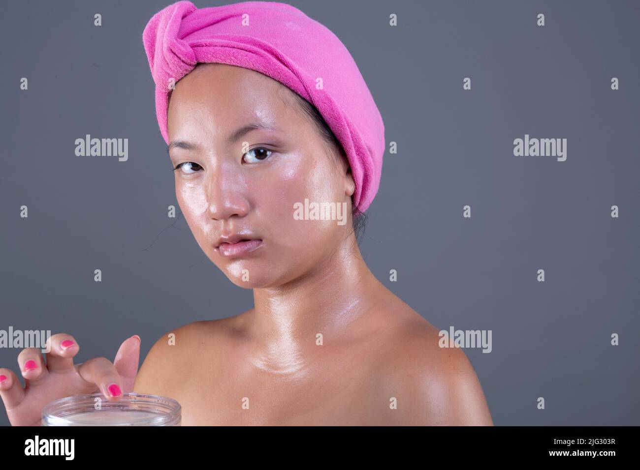 young woman of Chinese ethnicity taking care of her face with face cream Stock Photo