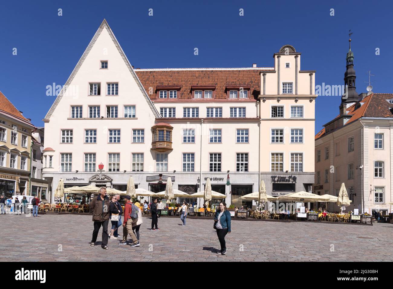 People in Tallinn old town Square Estonia - 14th century medieval buildings surrounding the old Town Hall square in summer; Tallinn, Estonia Europe Stock Photo