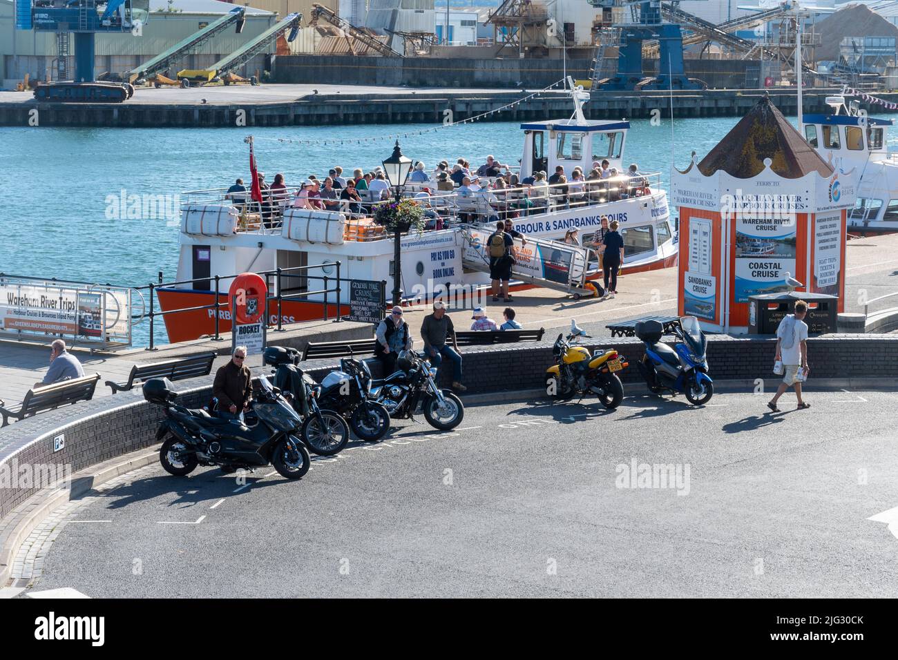 Motorbikes and a tour boat full of passengers at Poole Quay, Dorset, England, UK, on a sunny summer day Stock Photo