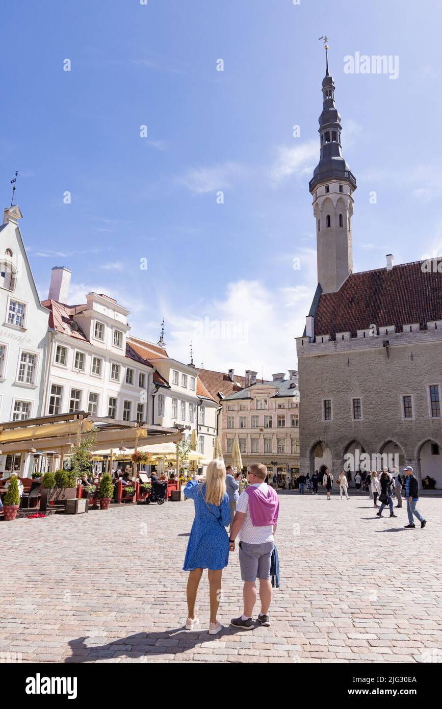 Tallinn tourists; a couple in Tallinn Old town square in front of Tallinn town Hall on holiday, Tallinn Town Hall square, Tallinn Estonia Europe Stock Photo