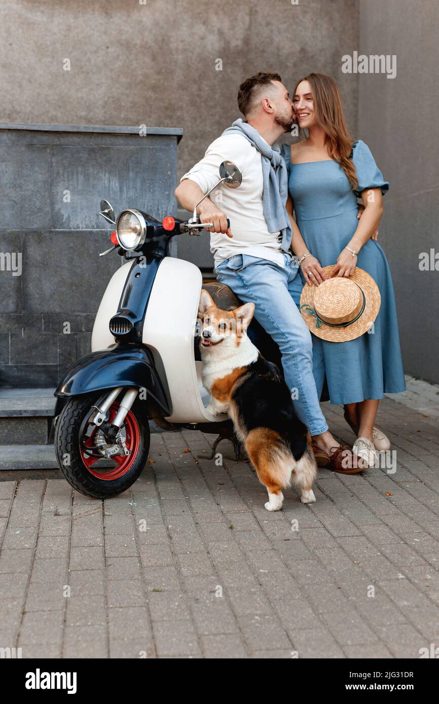Happy beautiful couple with dog on scooter in european city Stock Photo