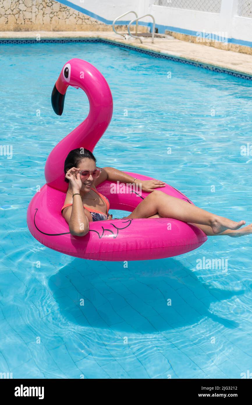 Portrait of confident woman relaxing, floating in inflatable ring in sunny summer swimming pool Stock Photo