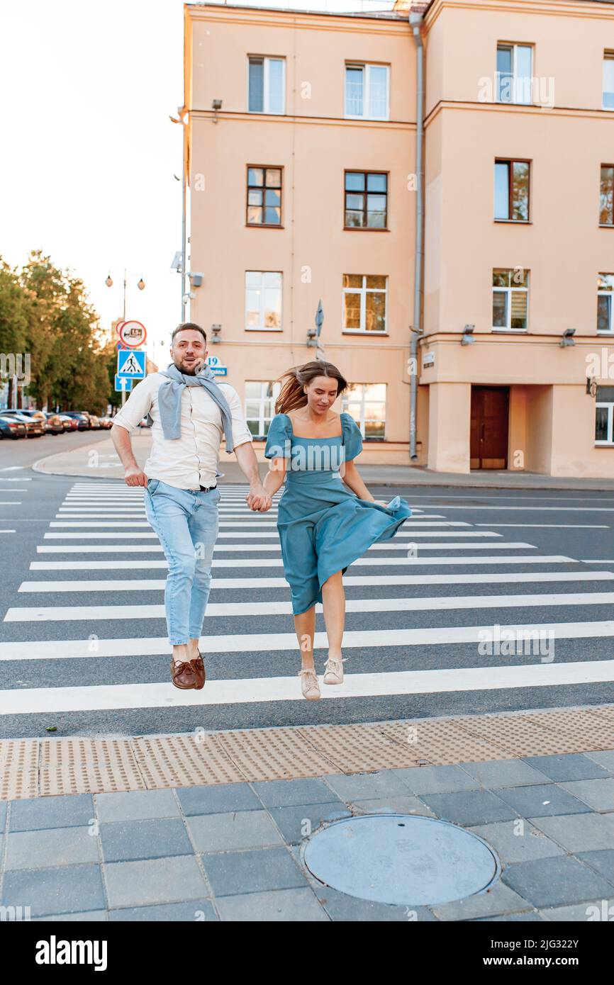 Romantic couple spending time together in the city and jumping while on a crosswalk. Stock Photo