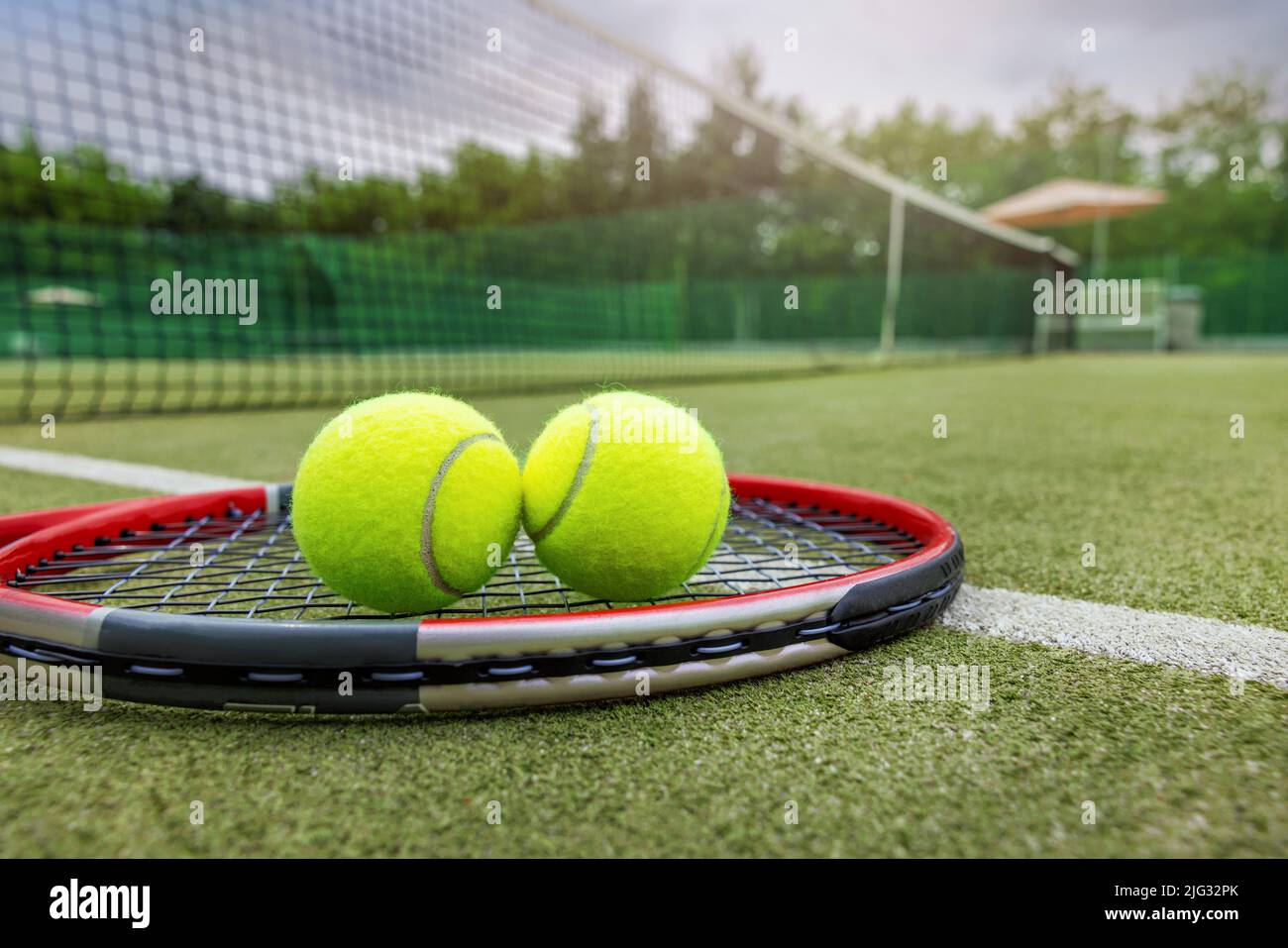 tennis racket and balls on synthetic grass outdoor court Stock Photo