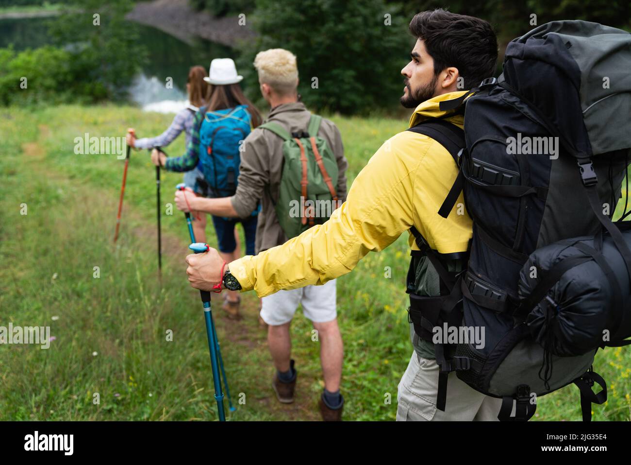 Group of friends with backpacks doing trekking excursion on mountain Stock Photo