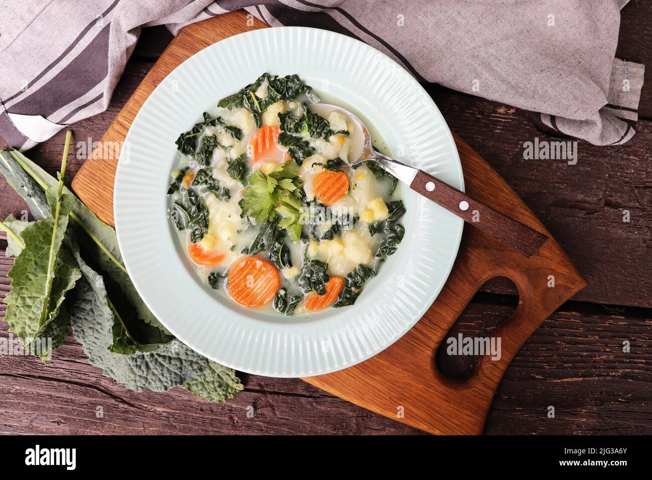Healthy vegetable soup with kale. Above view table scene on a dark wood background Stock Photo