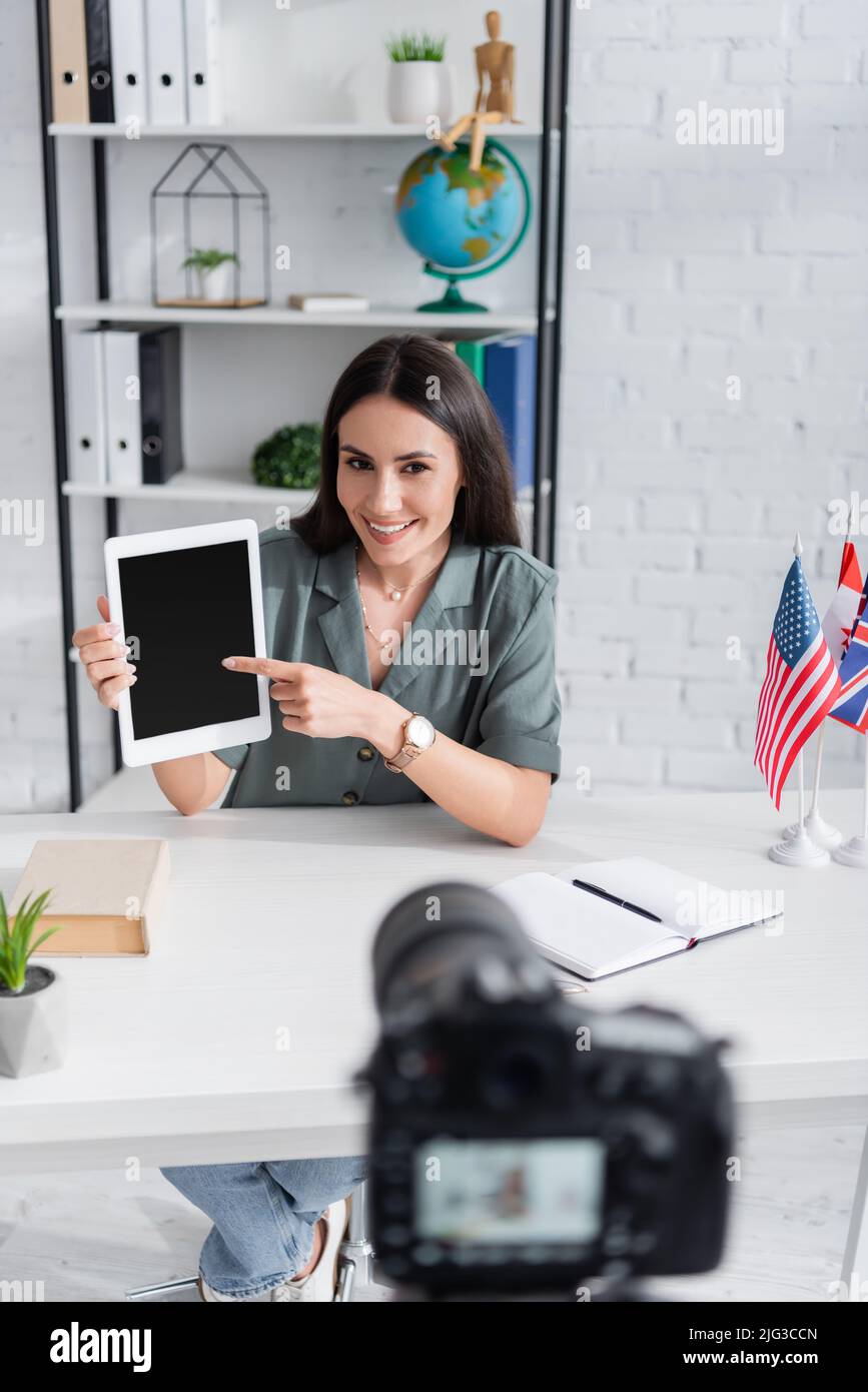 Teacher pointing at digital tablet near blurred camera and flags in class Stock Photo