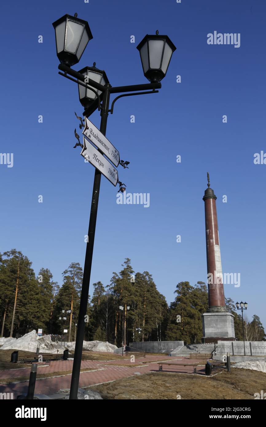 Light pole with signs near obelisk on the border between Europe & Asia near Ekaterinburg, Russia, indicating the distances to several major cities Stock Photo