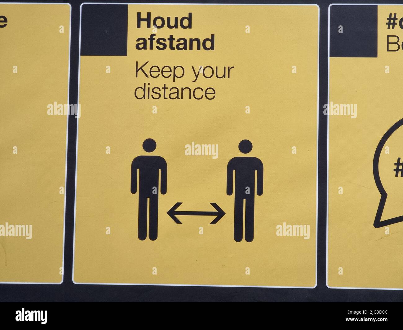 Dutch yellow sign depicting corona measures (Keep your distance, Houd afstand) at the bus station of Eindhoven Airport in the Netherlands Stock Photo