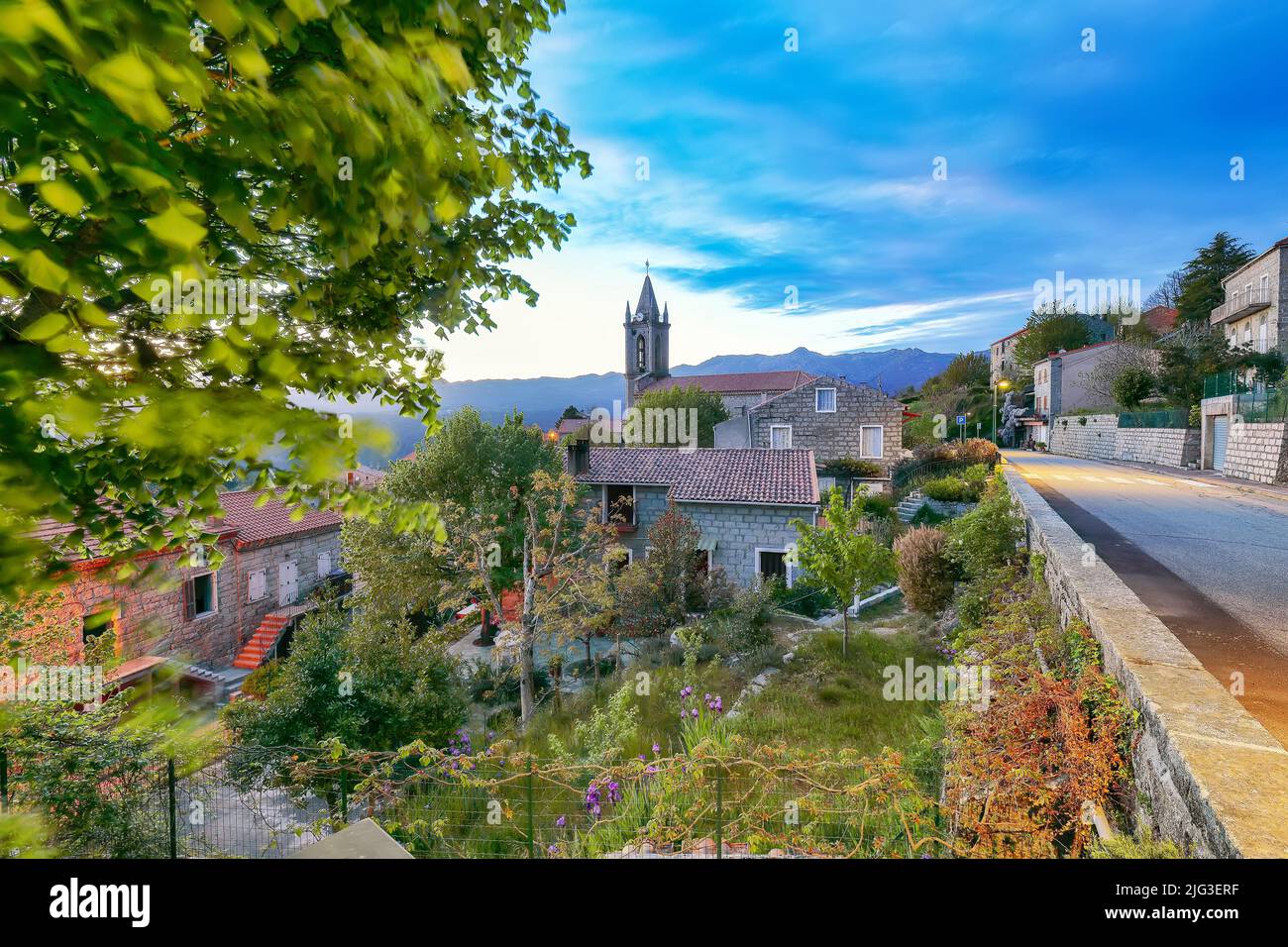 Majestic evening cityscape with Parish Church of the Assumption  in Zonza village with typical stone houses during sunset. Location: Zonza, Corse-du-S Stock Photo