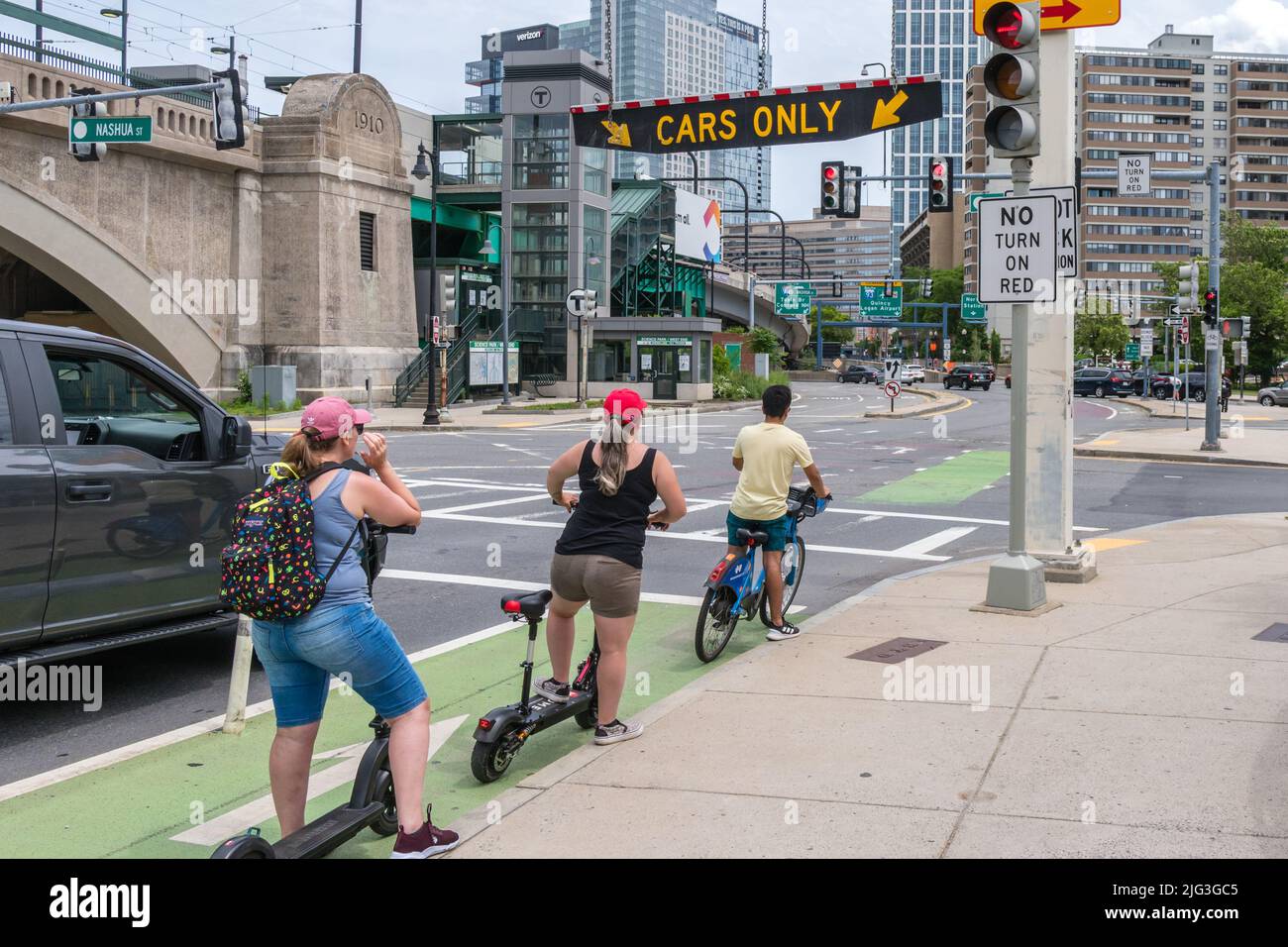 Boston, MA, USJune 11, 2022 People on bicycles and scooters in bike lane wait at traffic