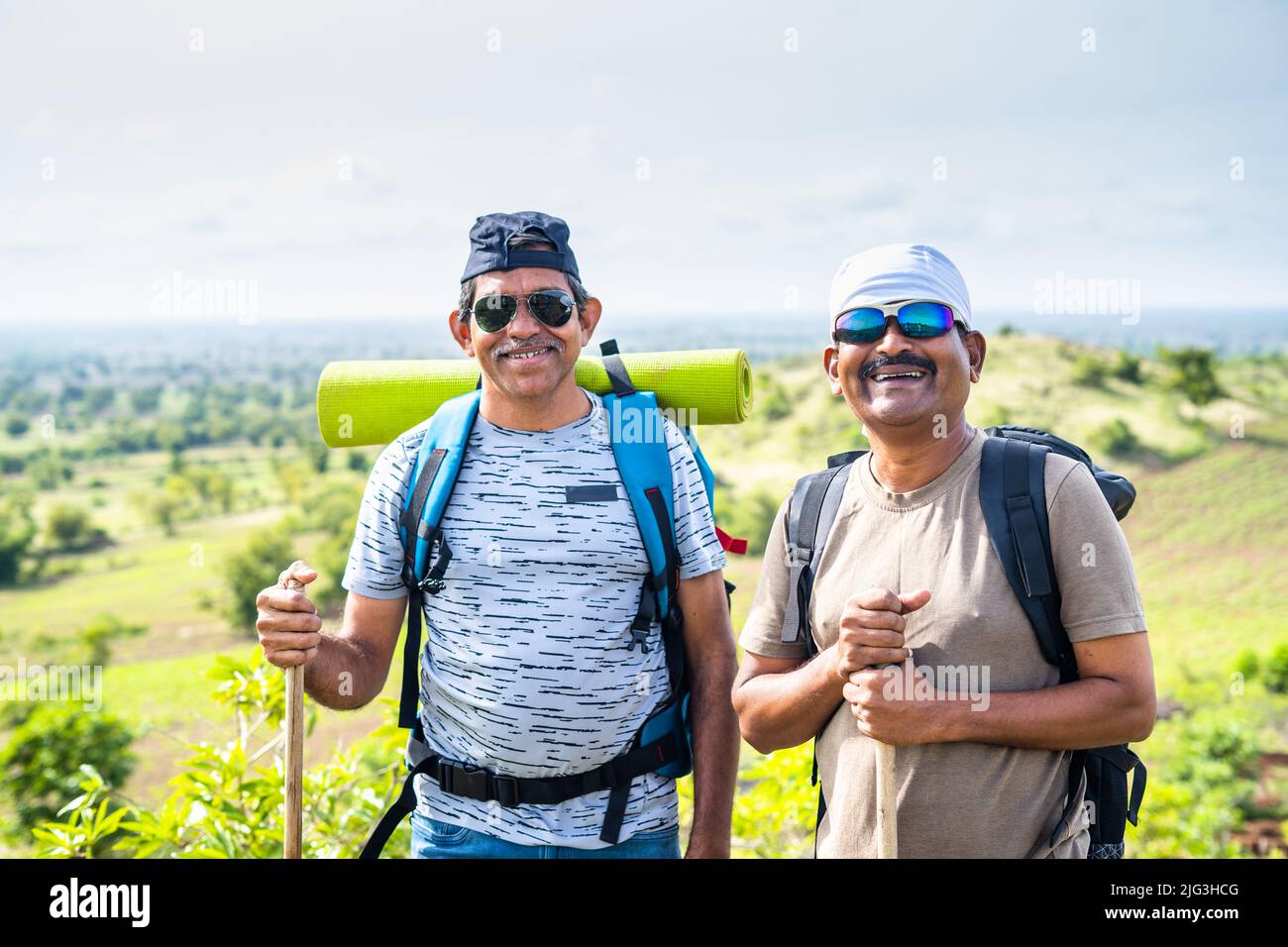 Happy smiling hikers or travellers with backpack looking at camera while trekking on mountain - concept of friendship, relaxation and leisure Stock Photo