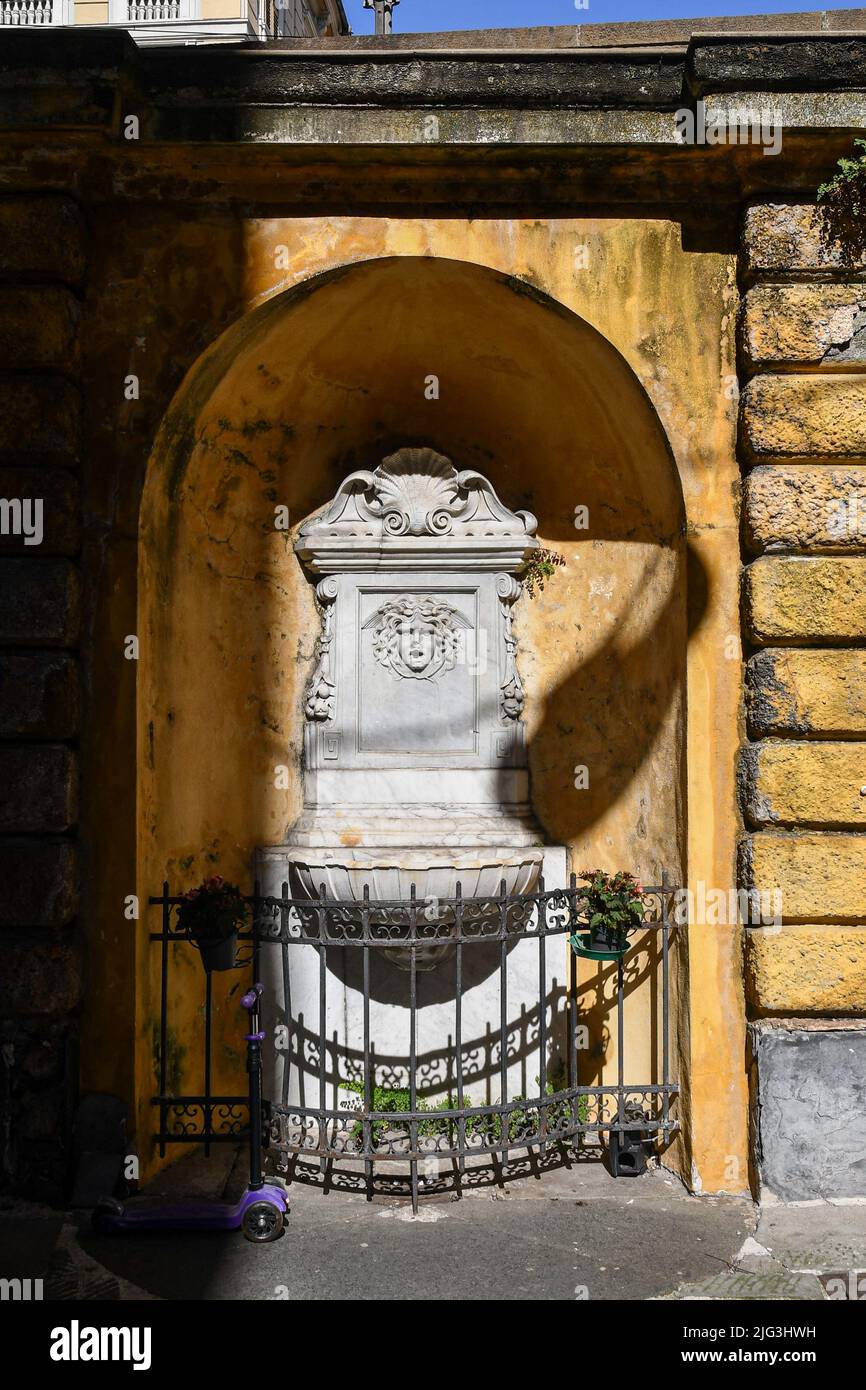 Detail of an ancient marble fountain in Via Luccoli, a narrow street in the historic centre of Genoa, decorated with a head of Medusa, Liguria, Italy Stock Photo