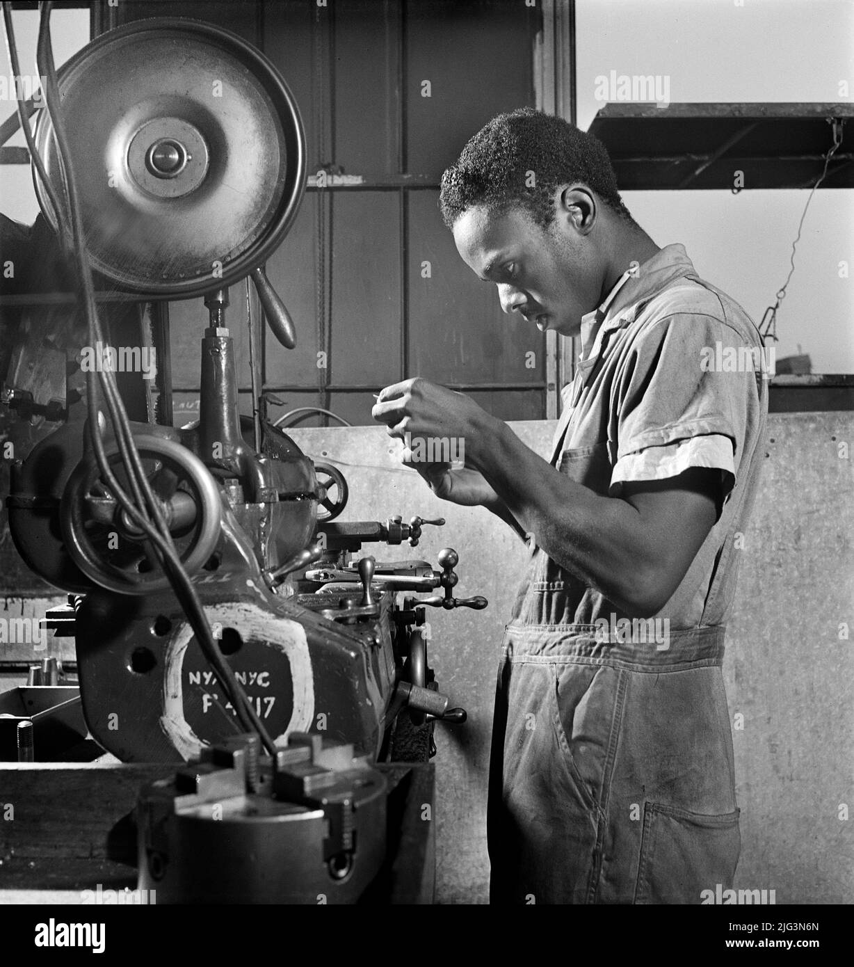Young Adult Man receiving training as a turret-lathe Worker, National Youth Administration (NYA) Work Center, Brooklyn, New York, USA, Fritz Henle, U.S. Office of War Information/U.S. Farm Security Administration, August 1942 Stock Photo