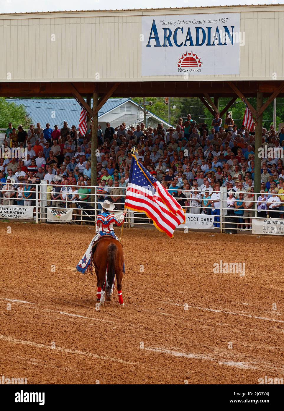 rodeo, US flag bearer, woman riding horse, stands, spectators, contest