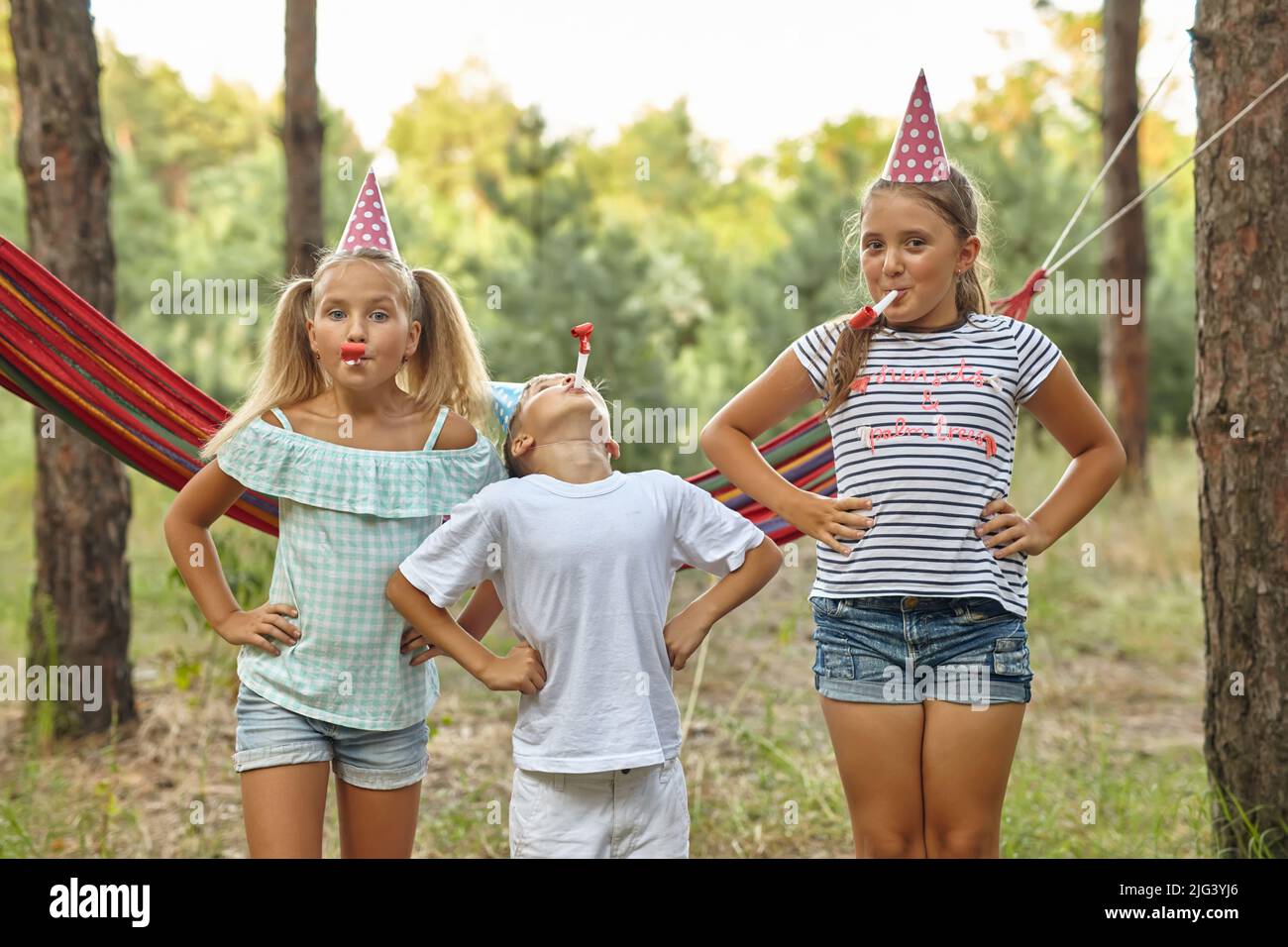 birthday, childhood and celebration concept - happy kids blowing party horns Stock Photo