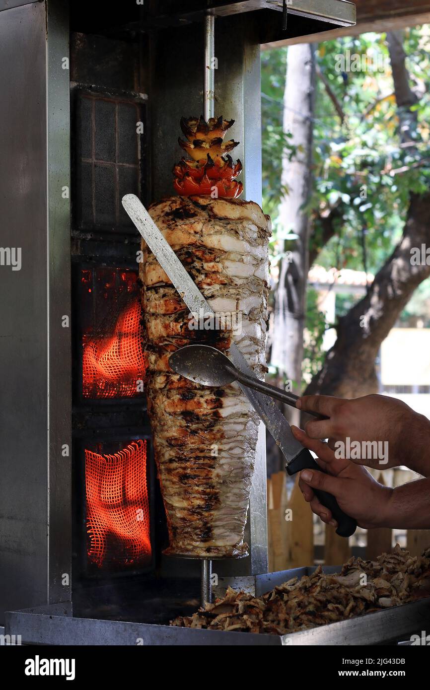 A chicken shawarma skewer roasting on a rotating pole. Stock Photo