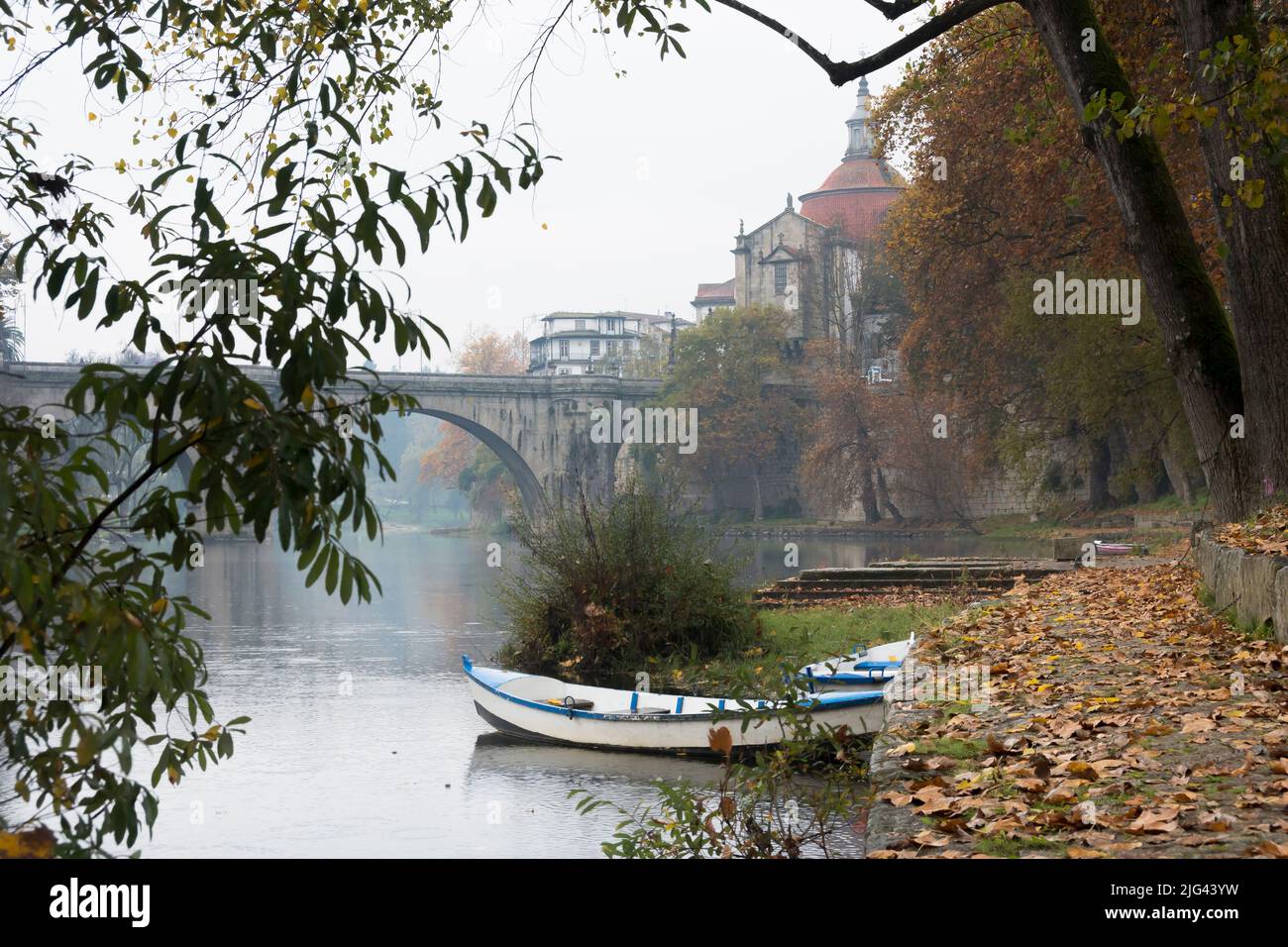 White rowing boat on the Tamega river near the historic bridge and Monastery and church of São Gonçalo. Amarante, Portugal. Stock Photo