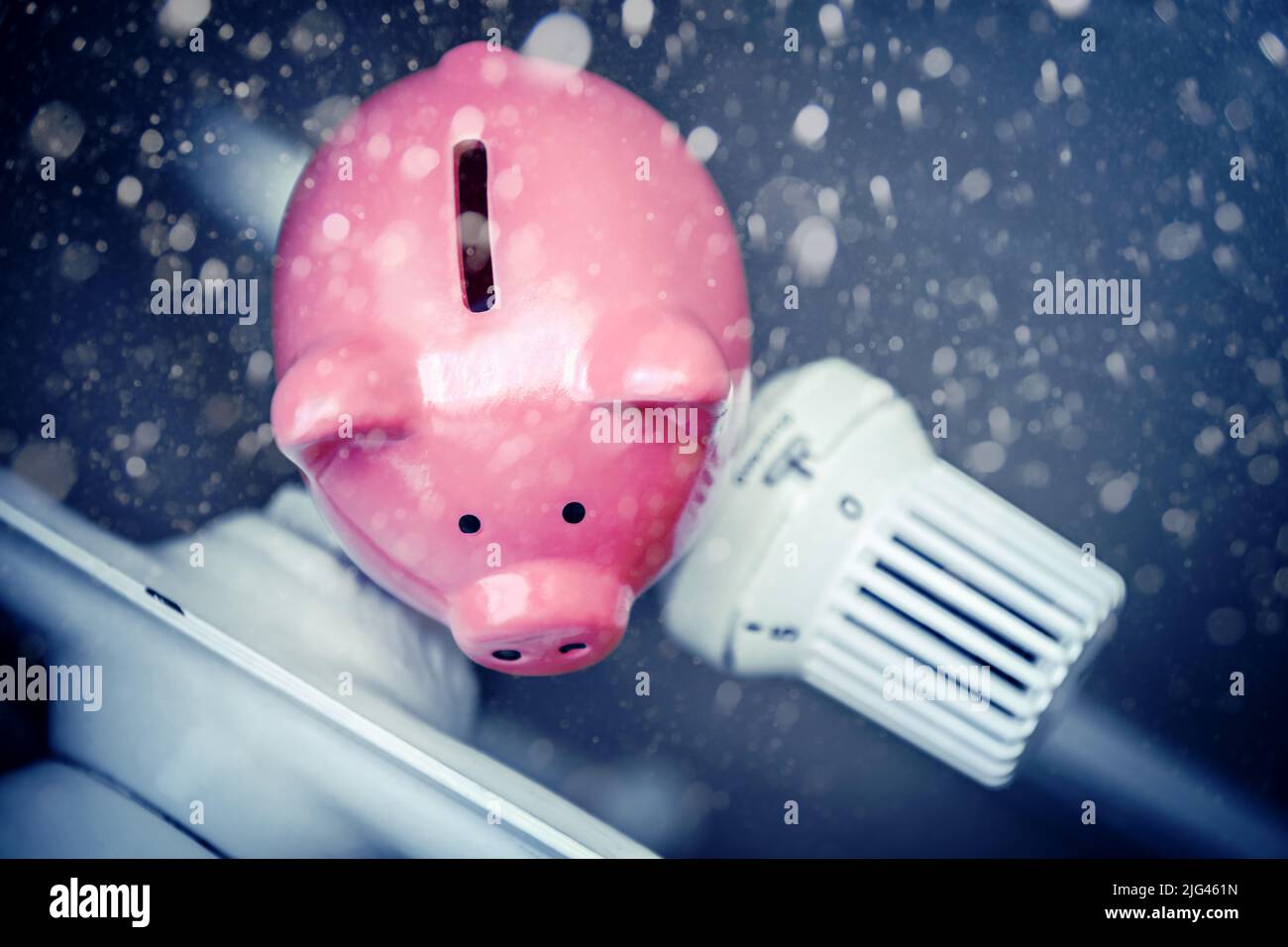 Piggy bank on a radiator and snowfall Stock Photo