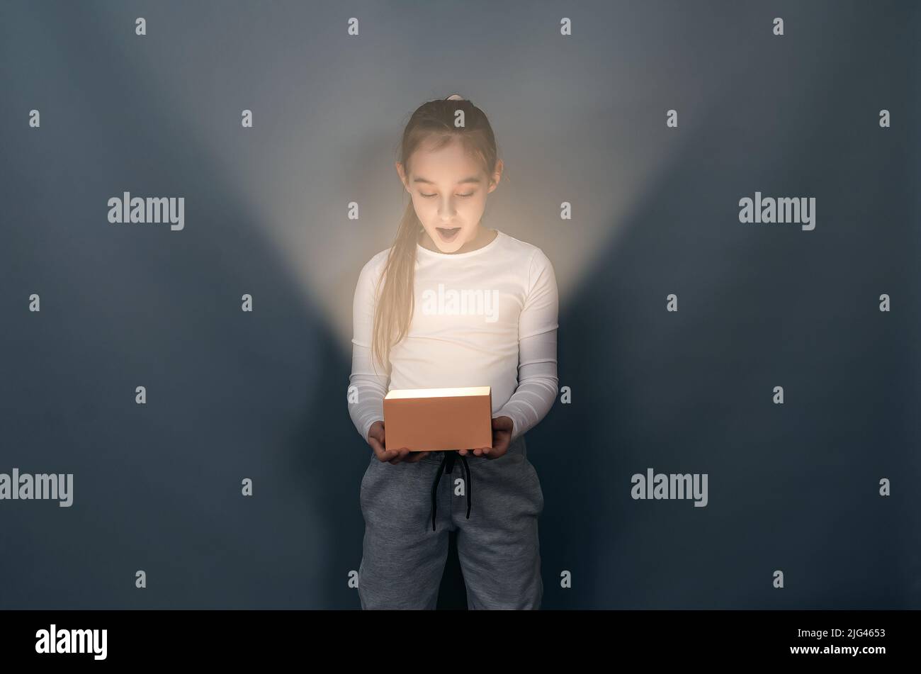 Shocked surprised child with glowing box. Interesting surprise. Gift. Stock Photo