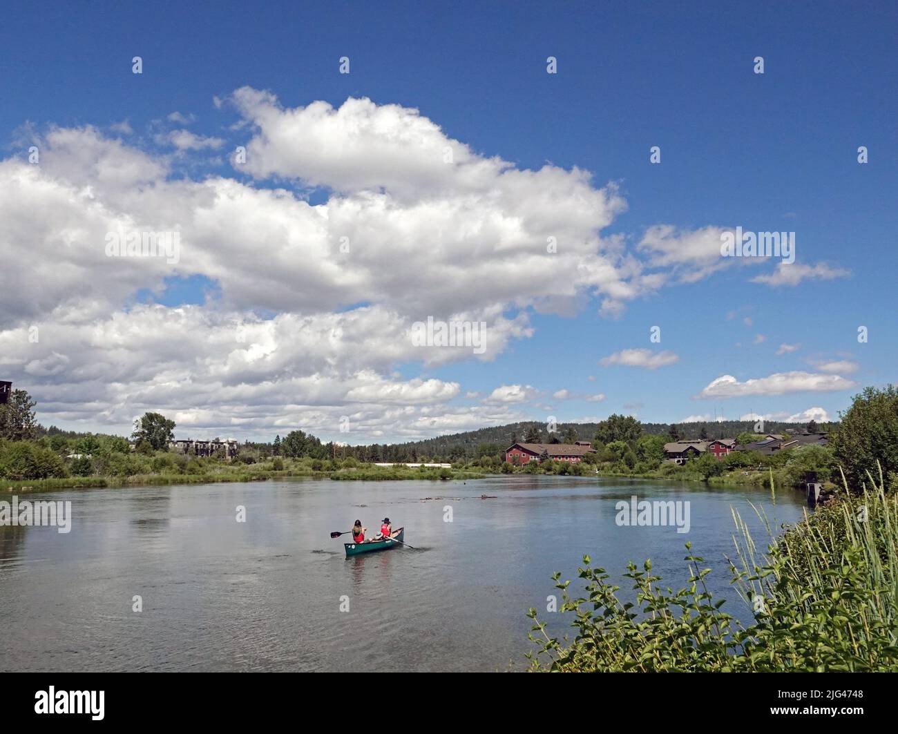 A canoe floats in the Deschutes River in the Old Mill Shopping District of Bend, Oregon. Stock Photo