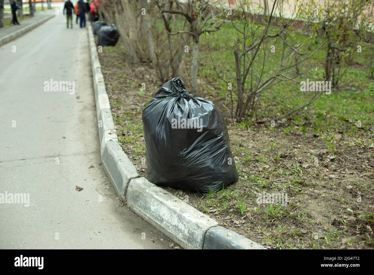 Bag is black. Garbage bag on road. Cleaning of territory. Plastic bag