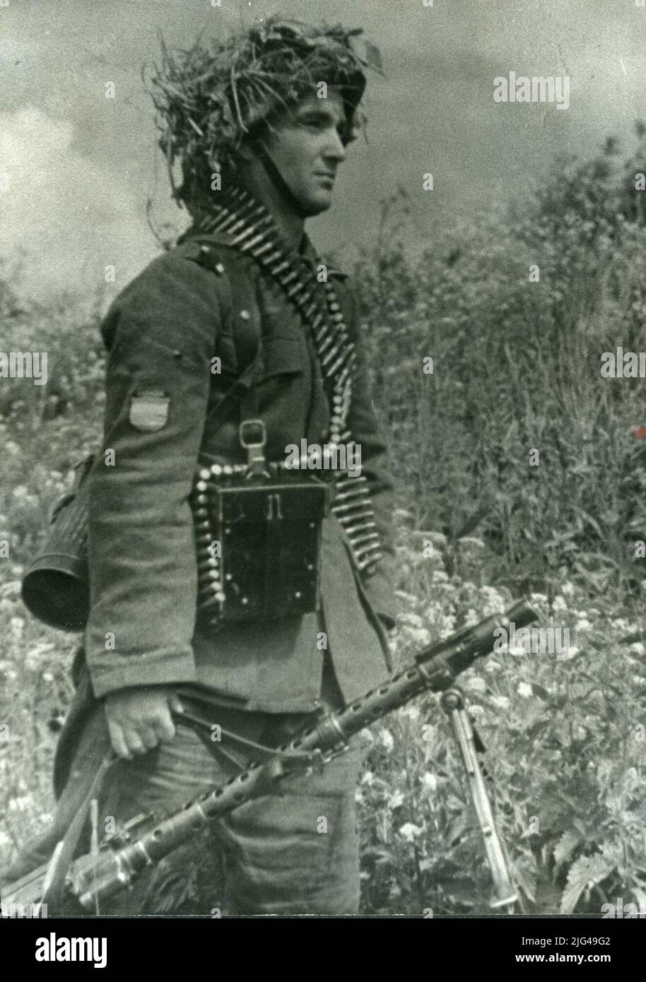 Machine gun shooter with an MG34, neck and box ammunition tape. Leningrad Front Unterogoffizier machine gun shooter with an MG34, neck and box ammunition tape with antigás. Helmet M 35 masked with herbs, and distinctive of the Spanish Volunteer Division. Leather strap and trenches, with RESPECT OF THE AML MODEL M1934. Stock Photo