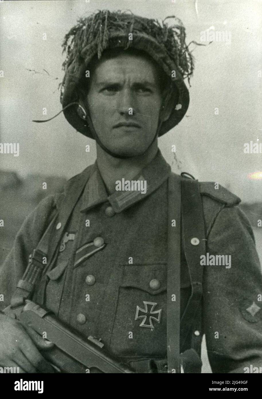1st Soldier (OberSchütze). Leningrad Front of 1st soldier (Oberschütze) with distinctive on his left arm, wears German uniform with eagle on his right pocket. He has the 1st class iron cross and the 2nd class, placed in the Spanish style (Warrior and Cross button on the left pocket of the warrior). M35 helmet, masked with herbs. He carries to the subfusil neck MP40. Stock Photo