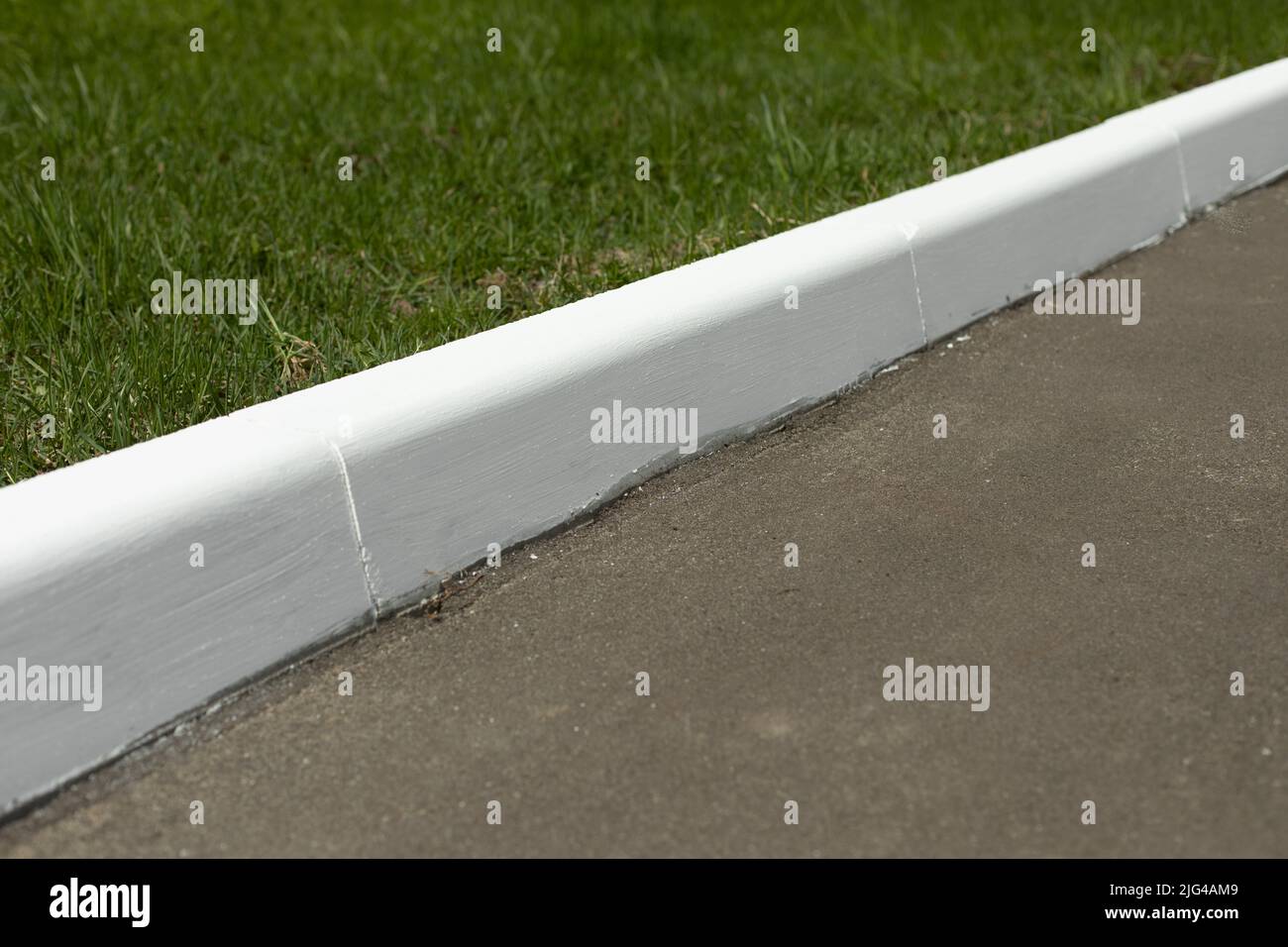 White curb on road. Landscaping in park. Painted curb Stock Photo Alamy
